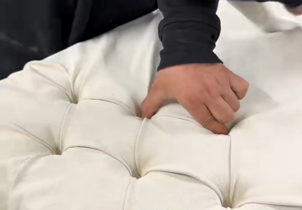 Hand-finishing a deep-buttoned upholstered panel in our factory